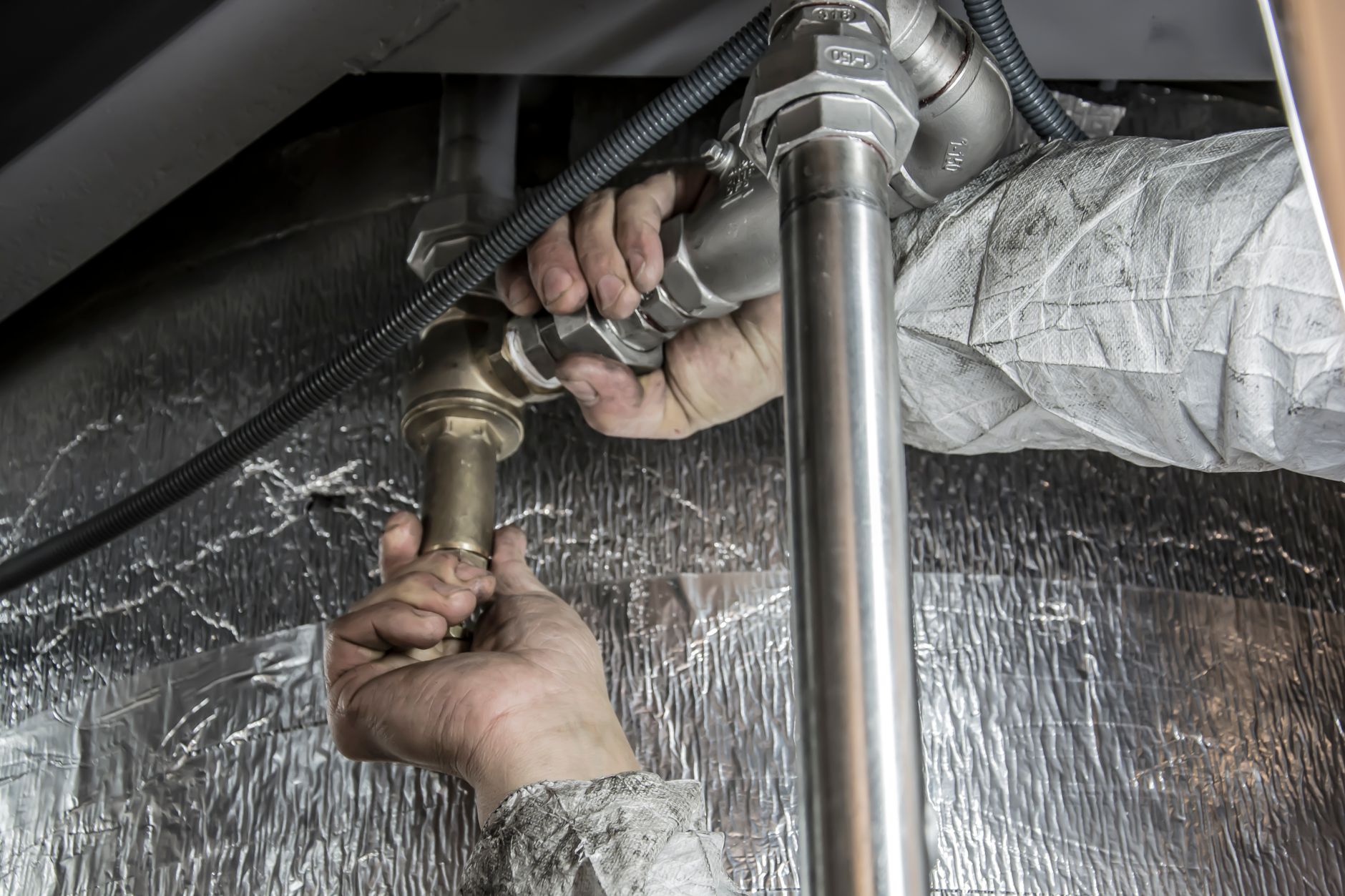 Close-up of hands fitting metal pipes indoors